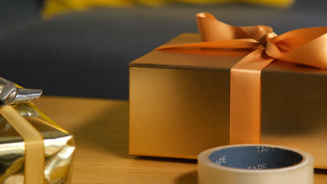 Close-Up-Of-Person-Gift-Wrapping-Present-On-Table-At-Home-With-Wrapping-Paper-And-Sticky-Tape